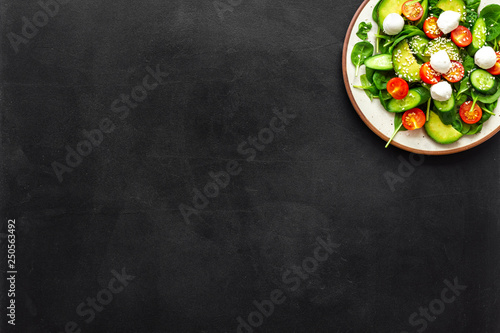 Healthy lunch. Fresh vegetable salad on black background top view space for text