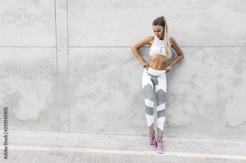 Model sport fitness w moda odzież sportowa pozowanie na szarej ścianie