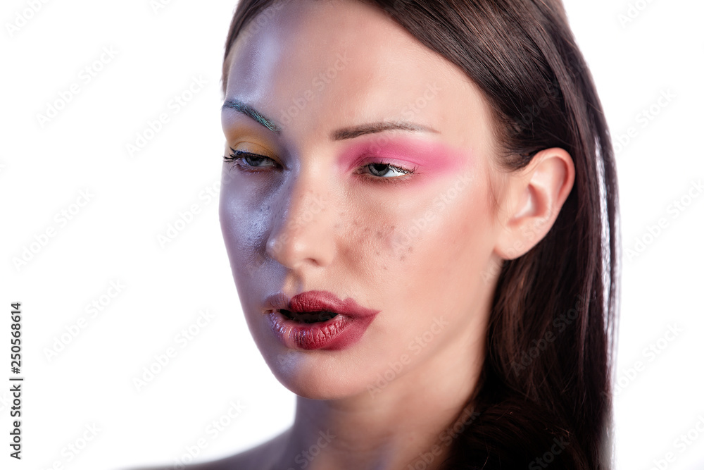 Young Caucasian Polish beauty model wears stunning cosmetics make-up that shows her stunning lips and bright colorful eye shadow in the studio . while she makes a funny face