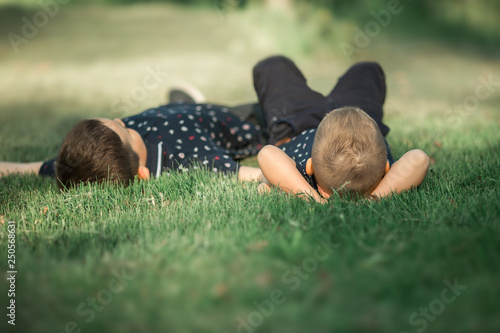 Children relax in nature. Brothers lie on the grass and watch the clouds