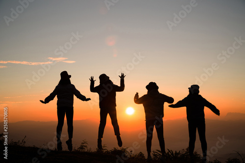 Silhouette of young woman are standing on top of the mountain relaxing with sunrise by nature at sunrise, Life style, Group of happy at sunrise or sunset, First morning light