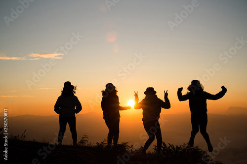 Silhouette of young woman are standing on top of the mountain relaxing with sunrise by nature at sunrise  Life style  Group of happy at sunrise or sunset  First morning light