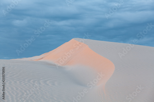 Beautiful white sand dune under cloudy sunset skies. Anna Bay, New South Wales, Australia