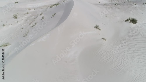 Aerial senital drone scene of dunes and sand desert with plants and the andes mountains on background. Camera moving forward close to the floor discovering landscape. Taton, Catamarca, Argentina photo