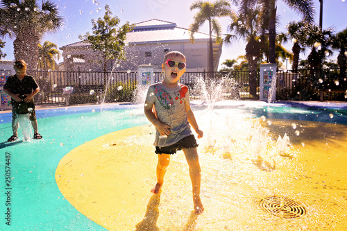 Little Child Playing in Water at Splash Park on Summer Day photo