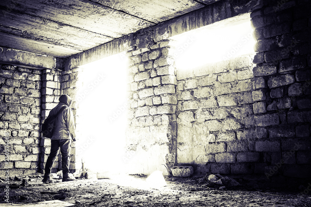Young man goint to bright light. Abandoned unfinished construction and a young man going to the doorway. 