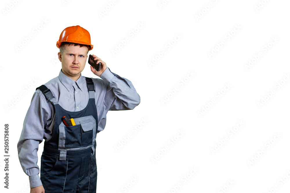 A young construction engineer is listening to something unpleasant on the phone. He is a little more focused on the information received on repair and construction. isolated