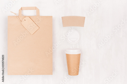 Eco friendly coffee template for design, advertising and branding - brown paper cup and blank bag, label, cap, copy space on white wood board, top view.