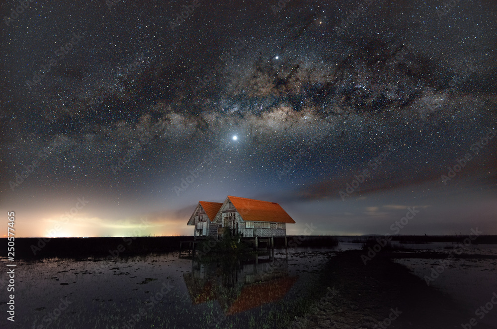 Milky way on clear sky day and abandoned house in wetland Thale noi, Phatthalung, Thailand.