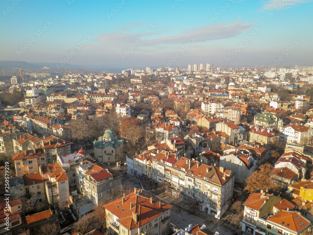 View from the height of the old town with low buildings with red tiled roofs against the blue sky and the clouds running over the horizon