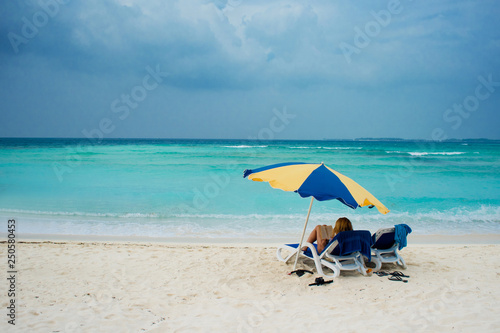 Rest on a tropical island. Lie in a sun lounger on the beach under an umbrella