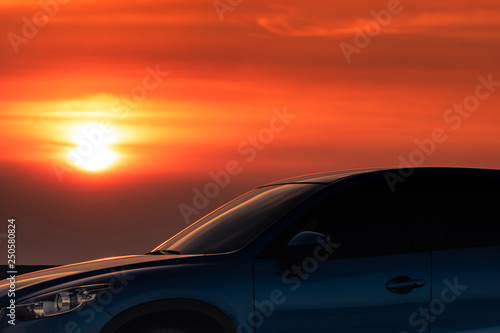 Blue compact SUV car with sport and modern design parked on concrete road by the sea at sunset in the evening. Hybrid and electric car technology concept. Car parking space. Automotive industry.