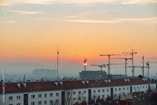 Sunset over a construction site in the south of Vienna - sun touching the horizon behind a crane.