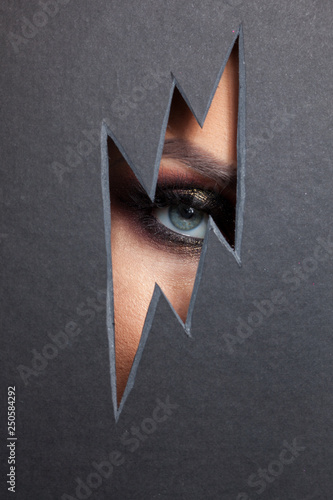 Beautiful female eye with color makeup. Cutout in paper in the form of a lightning.