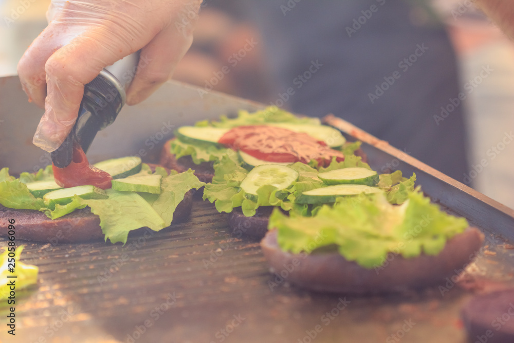 Burger buns are watered with ketchup. Street fast food during cooking Burger buns are watered with ketchup. Street fast food during cooking