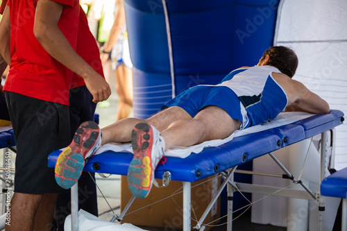 Athlete lying on a Bed while having Legs Massaged after a Physical Sports Workout photo