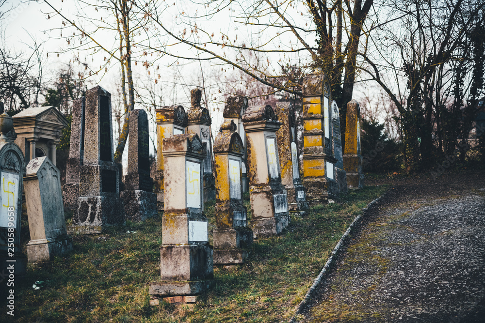 Side view of multiple vandalised graves with nazi symbols in yellow