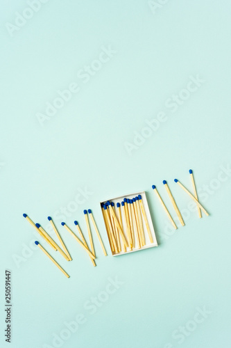 Bright wooden matches scattered from matchbox on a turquoise pastel color background