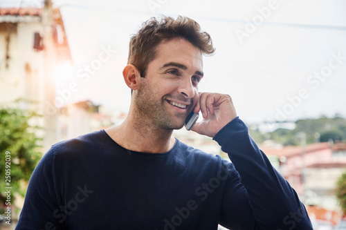 Handsome guy smiling on Smartphone, looking away
