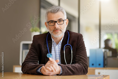 Εκτύπωση καμβά General practitioner sitting at his desk in medical office