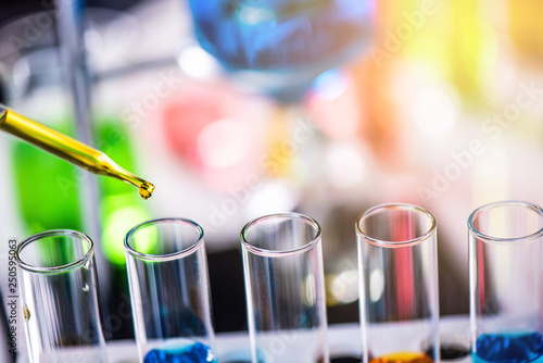 Using dropper sampling oil or chemical liquid drop to test tube with lab glassware in laboratory background, science or medical research and development concept