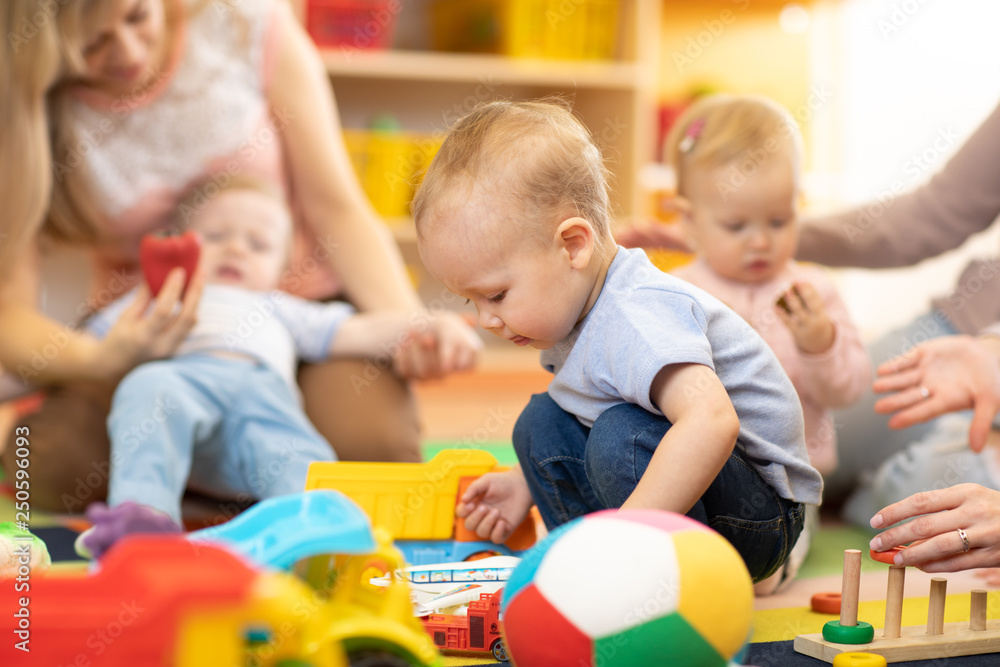 Nursery babies playing with adults in day care center Nursery babies playing with adults in day care center