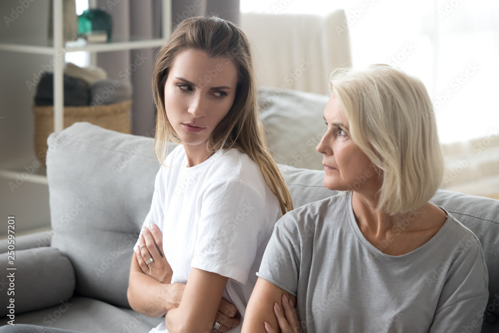 Angry aged mother and daughter looking at each other after quarrel Angry aged mother and daughter looking at each other after quarrel