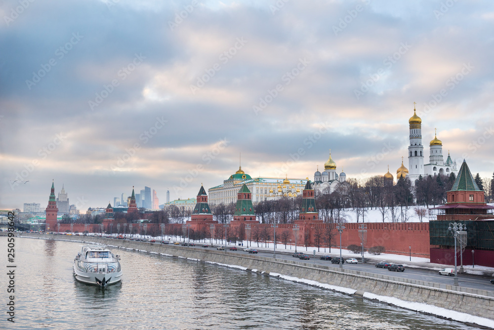 Kremlin embankment of the Moscow river, boat on the river at sunset, view of Moscow at sunset in winter