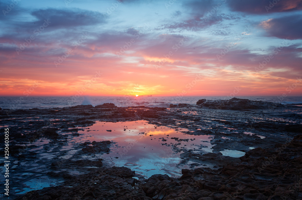 Sea coast sunrise and rock pool reflections