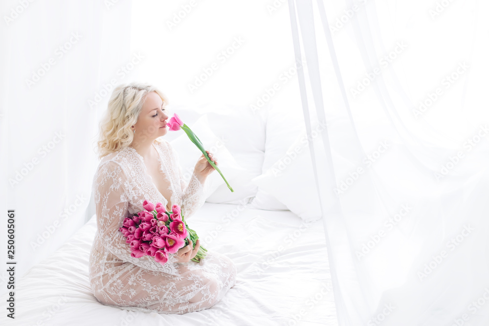 portrait of beautiful young woman with pink tulip. white bed room portrait of beautiful young woman with pink tulip. white bed room