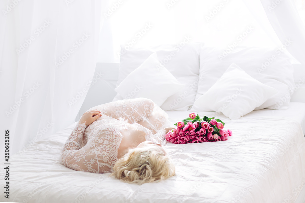 portrait of beautiful young woman with pink tulip. white bed room