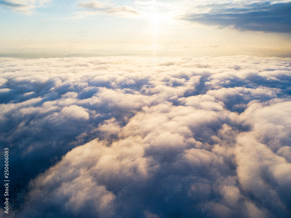 Aerial view White clouds in blue sky. Top view. View from drone. Aerial bird's eye view. Aerial top view cloudscape. Texture of clouds. View from above. Sunrise or sunset over clouds