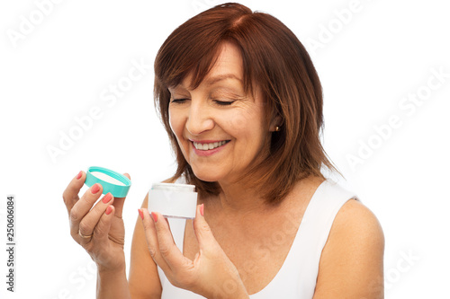 beauty, skincare and cosmetics concept - smiling senior woman with cream jar