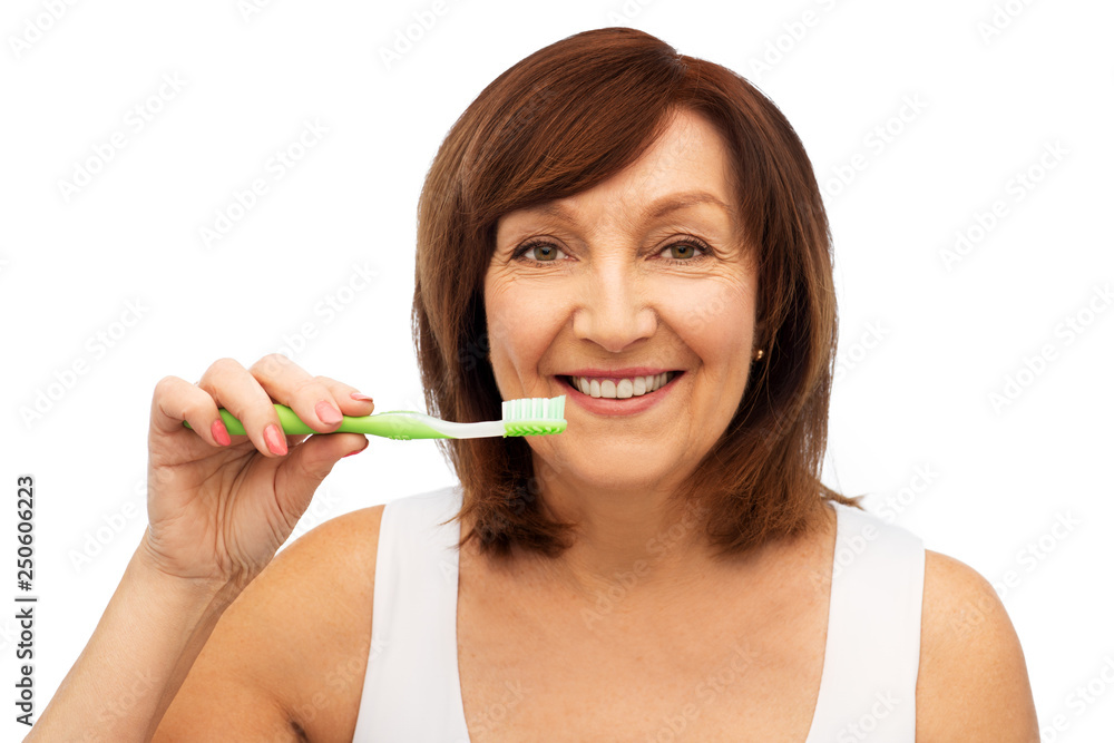 dental care and hygiene people concept - portrait of smiling senior woman with toothbrush brushing her teeth over white background dental care and hygiene people concept - portrait of smiling senior woman with toothbrush brushing her teeth over white background