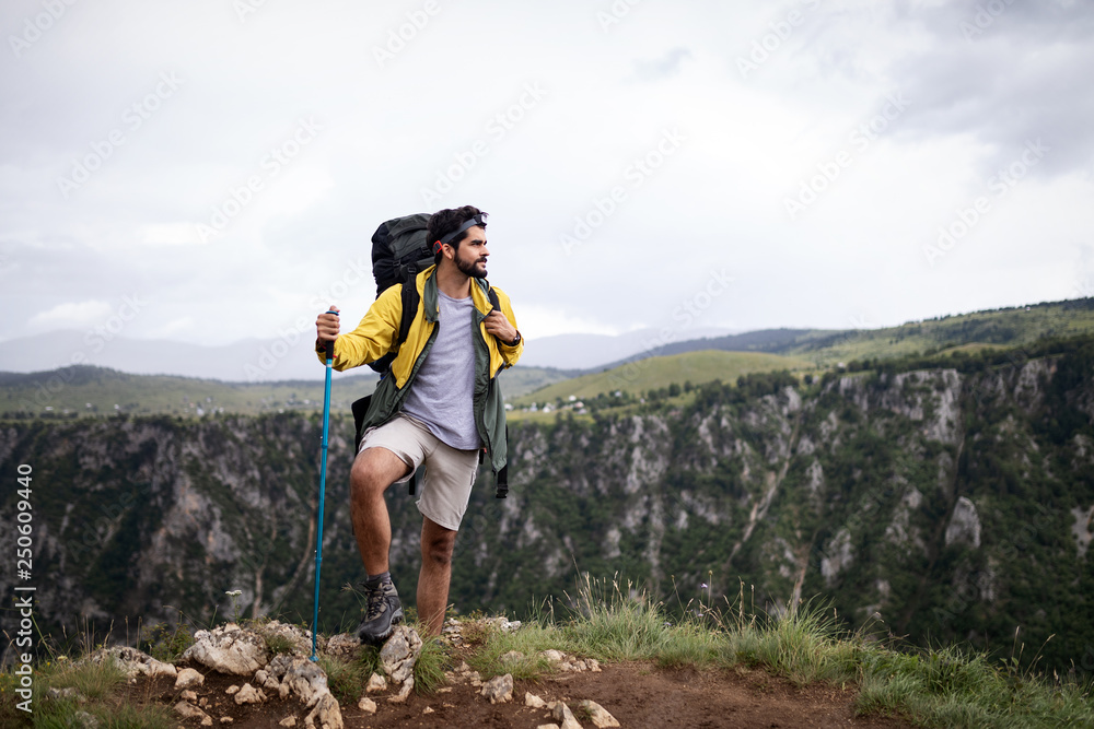 Obraz premium Young man traveling with backpack hiking in mountains