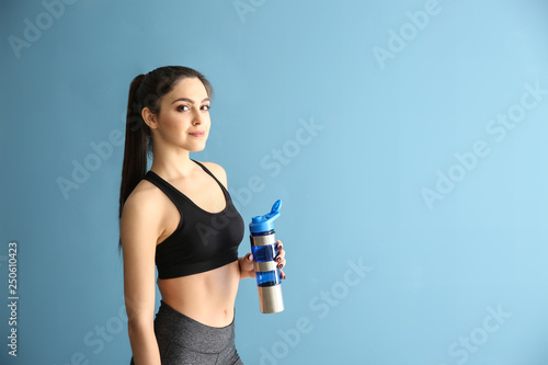 Sporty young woman with bottle of water on color background © Pixel-Shot