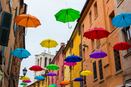 Colorful umbrellas floating in the sky above the ancient UNESCO listed town centre of Ferrara, Italy. photo
