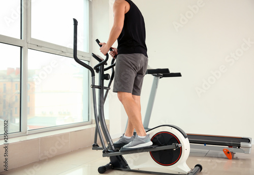 Sporty young man using modern machine in gym