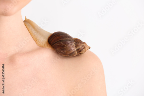 Young woman with giant Achatina snail on light background, closeup