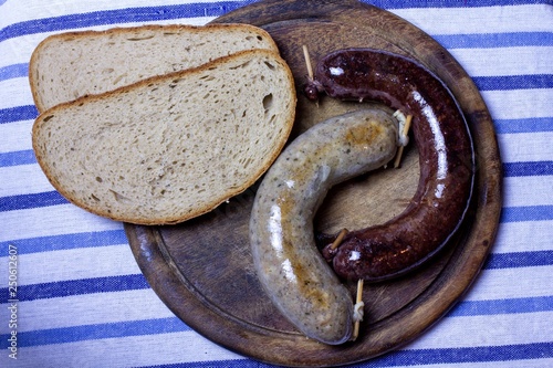 Products made of genuine Czech (central European) pig slaughter. Sausage and black sausage on wooden board with bread. Bold and fleshy food. The product of the traditional home-slaughter. 