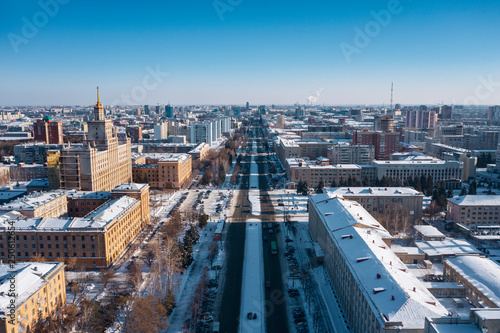Aerial  drone panoramic view of Chelyabinsk snow cityscape  winter city forest with pine trees on background  main street with cars  center of science and development  education system of engineering