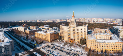 Aerial; drone panoramic view of Chelyabinsk snow cityscape; winter city forest with pine trees on background; main street with cars; center of science and development; education system of engineering