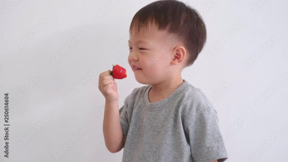 Cute happy smiling little Asian 2 -3 years old toddler baby boy child using hands eating strawberry, Healthy snacks & Self feeding concept Cute happy smiling little Asian 2 -3 years old toddler baby boy child using hands eating strawberry, Healthy snacks & Self feeding concept