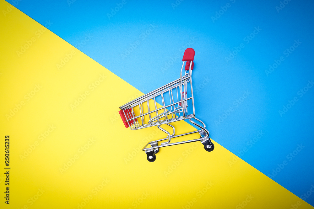Shopping cart on blue and yellow background, business and shopping concept. Selective focus Shopping cart on blue and yellow background, business and shopping concept. Selective focus