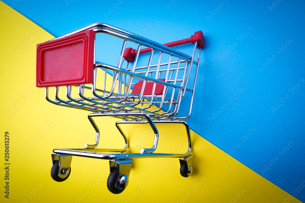 Shopping cart on blue and yellow background, business and shopping concept. Selective focus