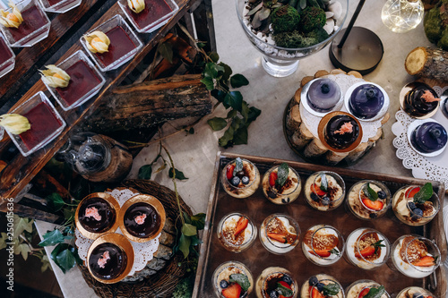 Delicious desserts and cakes with blueberries and strawberries on a beautifully decorated table with wooden elements