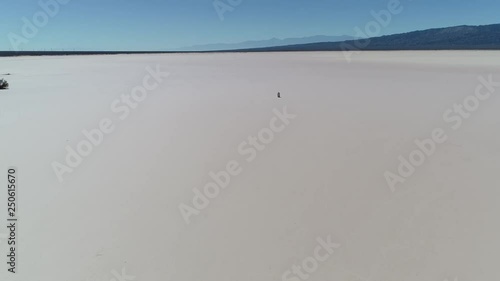 Aerial drone scene of arid dry barreal desert in aimogasta, la rioja, argentina. Camera moving forward to an empty land full of car tracks. Mountains on the background. photo