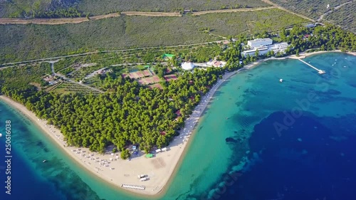 Aerial bird's eye view video taken by drone of exotic seascape and sandy beach with turquoise clear waters and pine trees, Gregolimano, North Evoia island, Greece photo