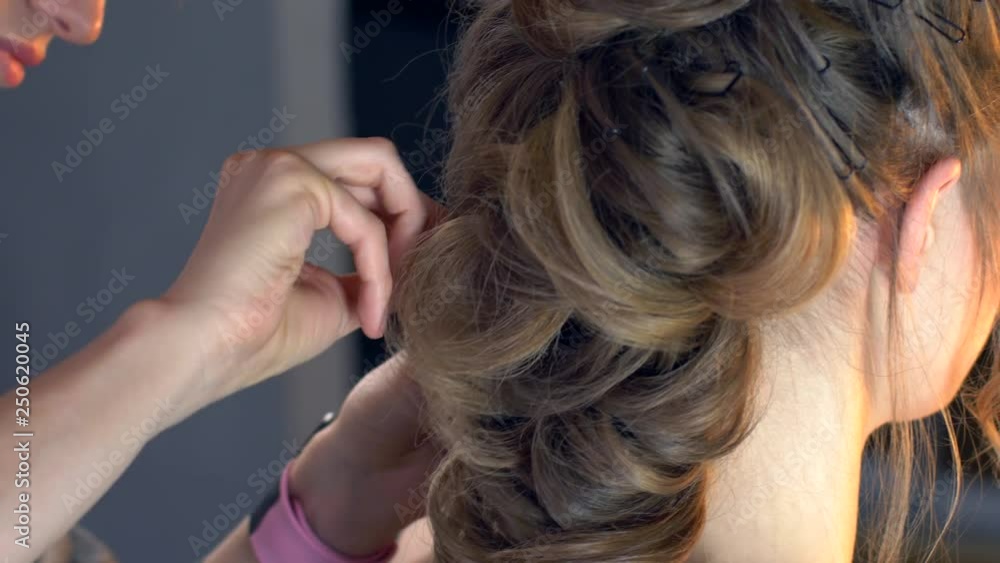 Makeup artist and hairdresser are preparing bride before wedding. Hairdresser-stylist with short stylish hairstyle applies makeup, makes false eyelashes, paints lips, curls girl, spectacular lighting Makeup artist and hairdresser are preparing bride before wedding. Hairdresser-stylist with short stylish hairstyle applies makeup, makes false eyelashes, paints lips, curls girl, spectacular lighting