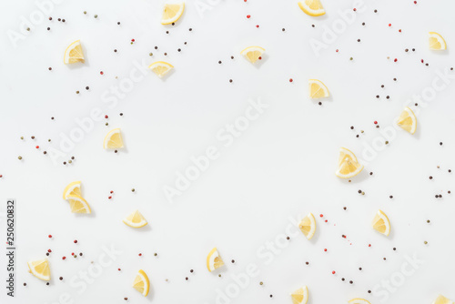 flat lay of lemon slices near red and black peppercorns isolated on white